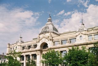 An ornate cream building with domes and the word HILTON on top, under a blue sky with clouds.