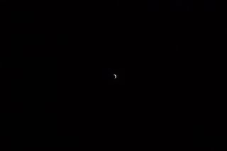 A tiny crescent moon in the middle of an almost entirely black frame.