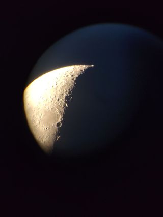 A close-up of the lit half of the moon showing craters, inside a dark blue circle.